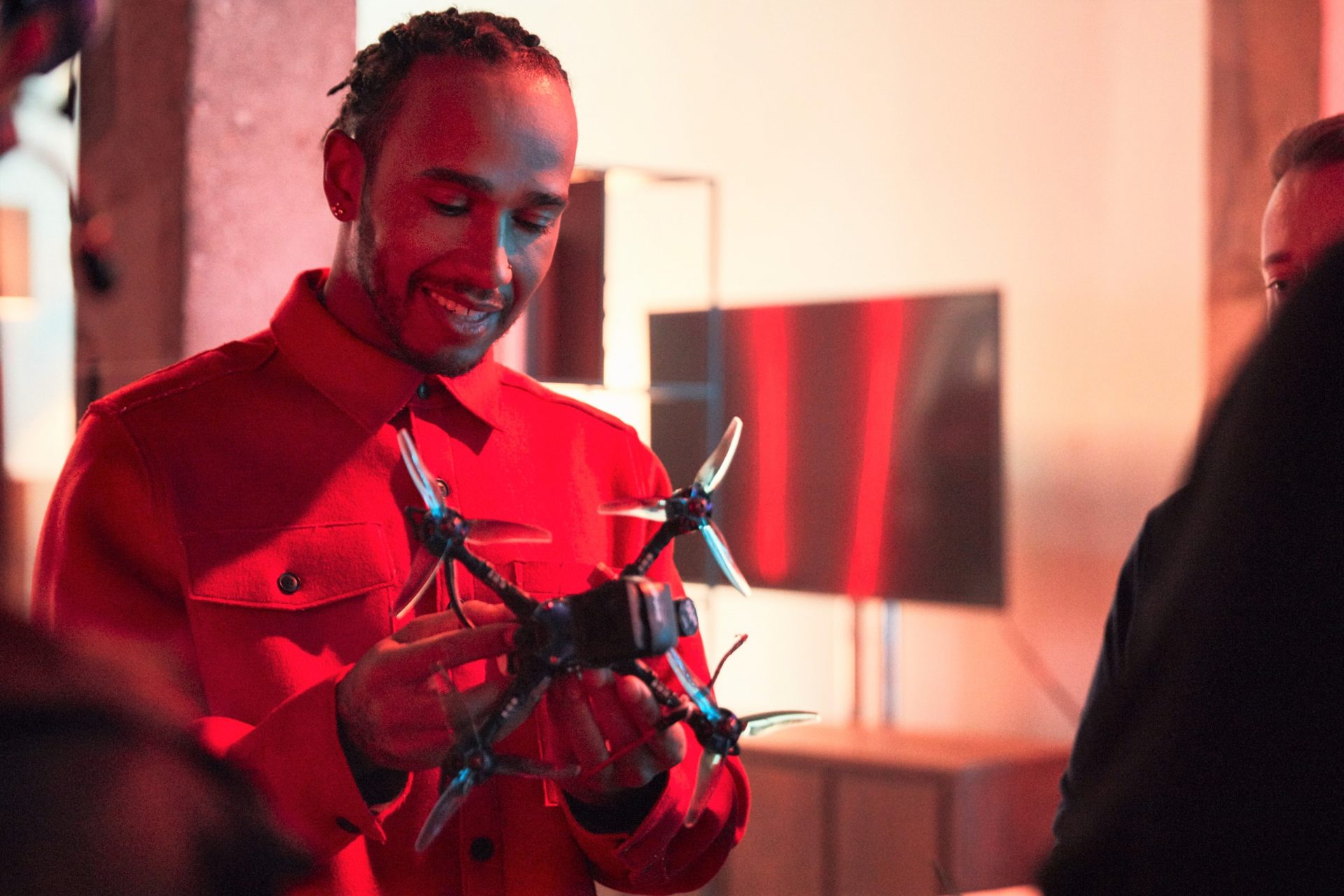 Lewis Hamilton smiling while inspecting a racing drone