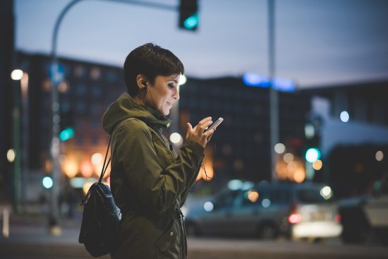 Woman checking smartphone at night in city setting