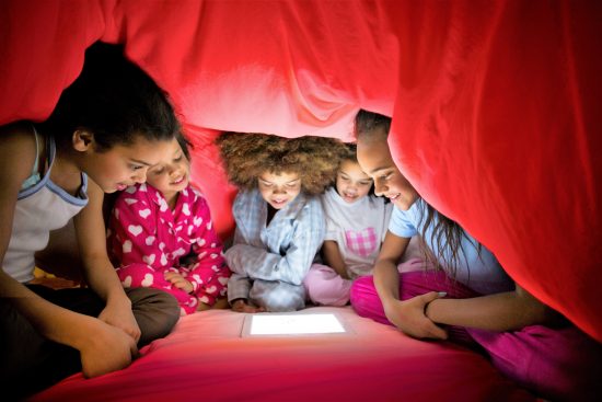 photo of children using their tablet underneath a blanket tent