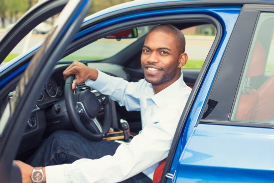 Young smiling man sitting in new car