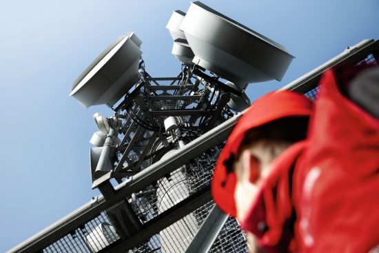 photo of a Vodafone engineer looking up at a Vodafone network mast