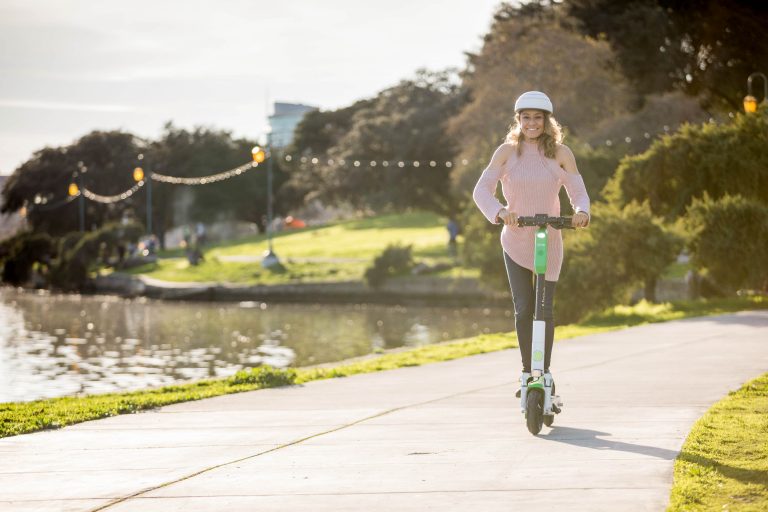 Young woman riding Lime Gen3 scooter next to lake