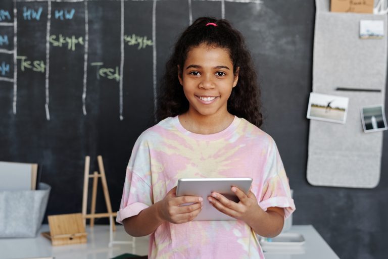 Smiling girl holding tablet in classroom