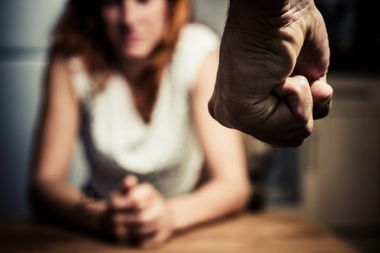 Domestic abuse: man with clenched fist, sitting woman in background