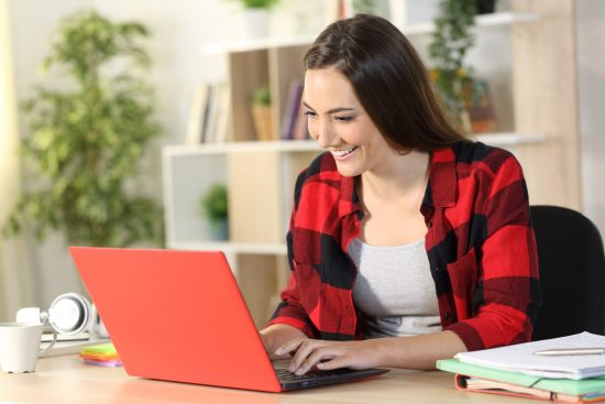 Young smiling woman working on red laptop