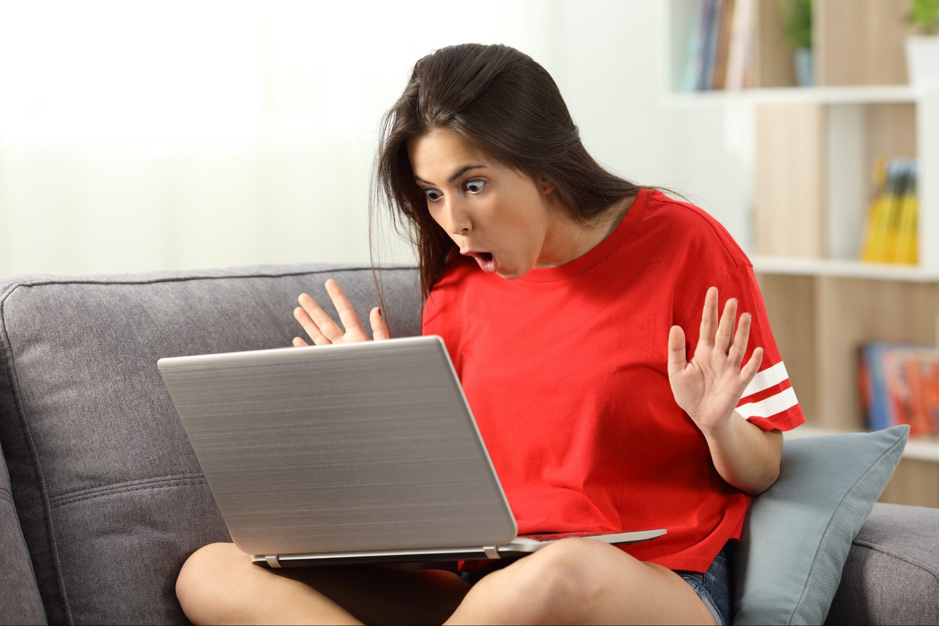 Surprised young woman looking at laptop