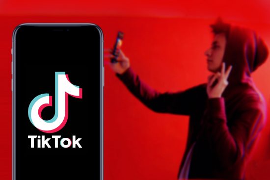 TikTok logo and boy taking selfie on red backround