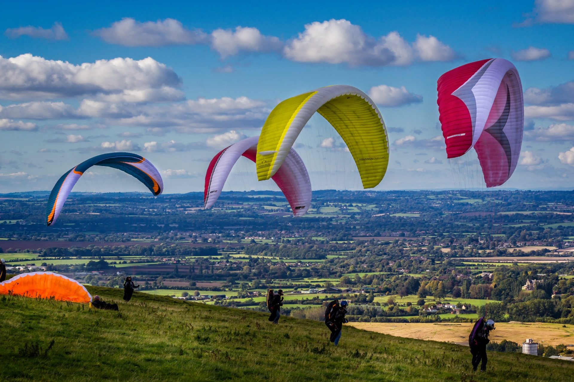 Four paragliders on UK hillside ready for take-off