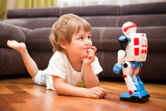 Young boy lying on floor staring at toy robot