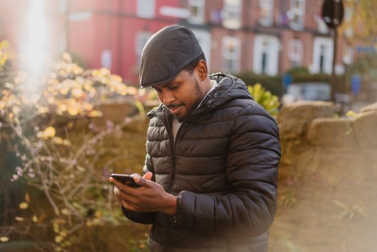 illustrative photo of a man using a smartphone outside