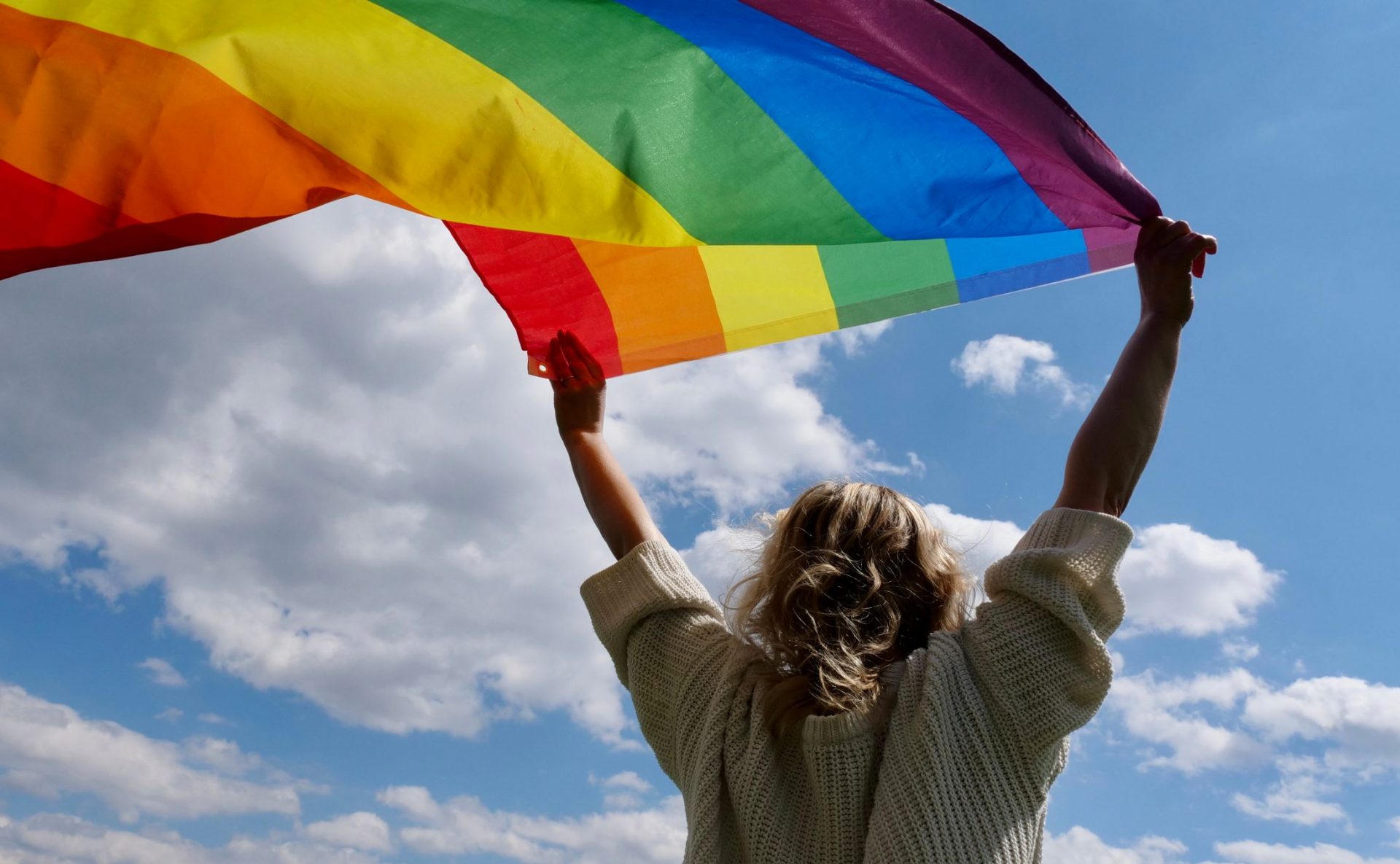 Young woman holding up rainbow flag
