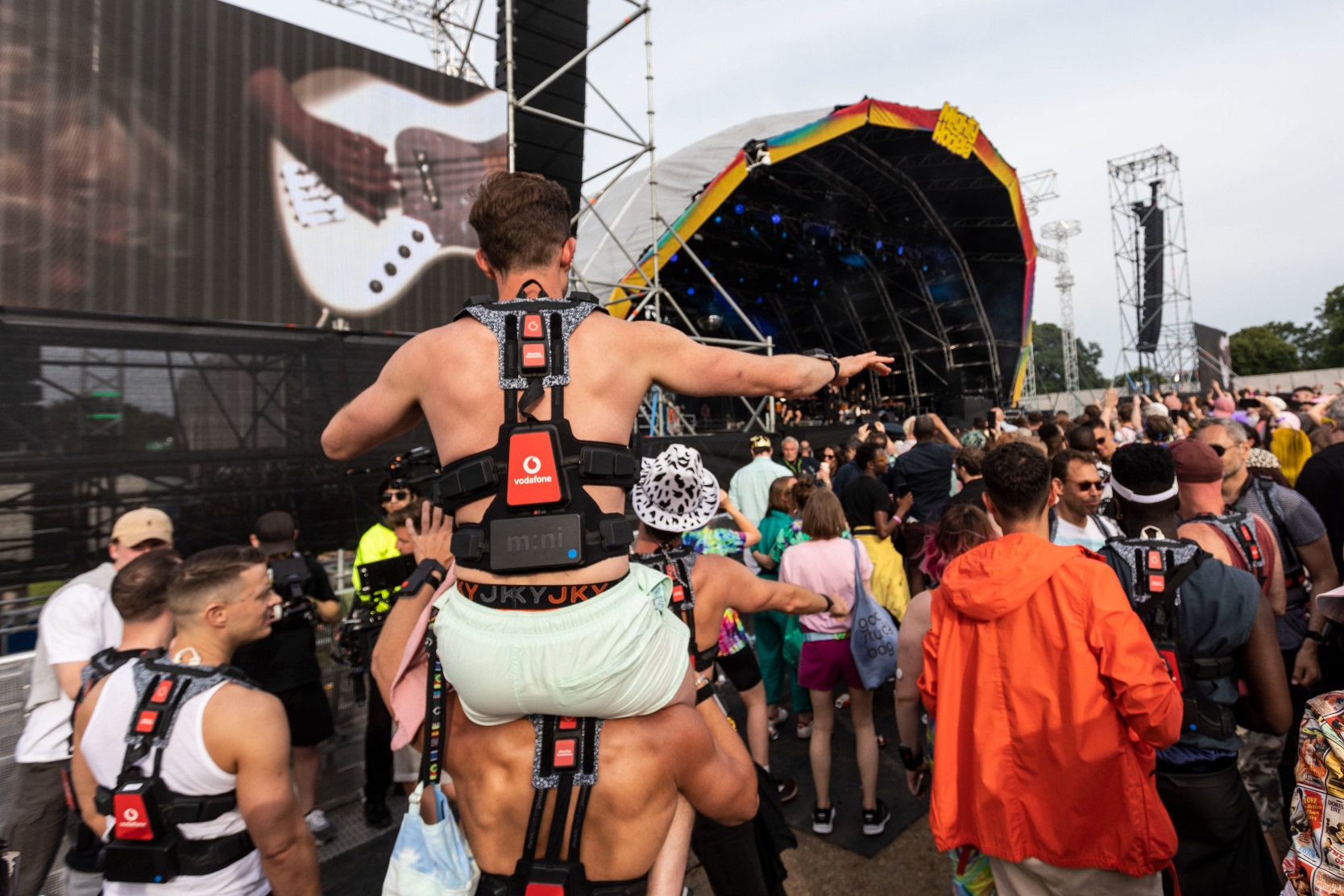 rear view of festival goers wearing Vodafone 5G haptic suits at Mighty Hoopla with the stage visible in the background.